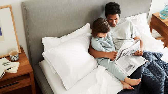 Father and child read on their CasperCalifornia King memory foam mattress