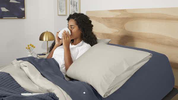 Woman drinking from mug in bed
